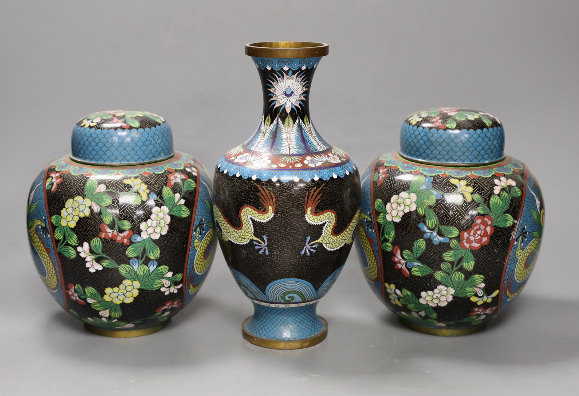 A pair of early 20th century Chinese cloisonné enamel ‘dragon’ jars and covers and a similar vase. Tallest 25.5cm